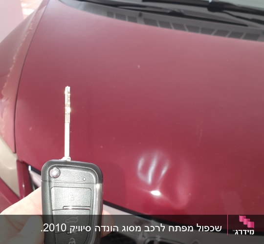 מפתח רכב מול מכסה מנוע של רכב אדום